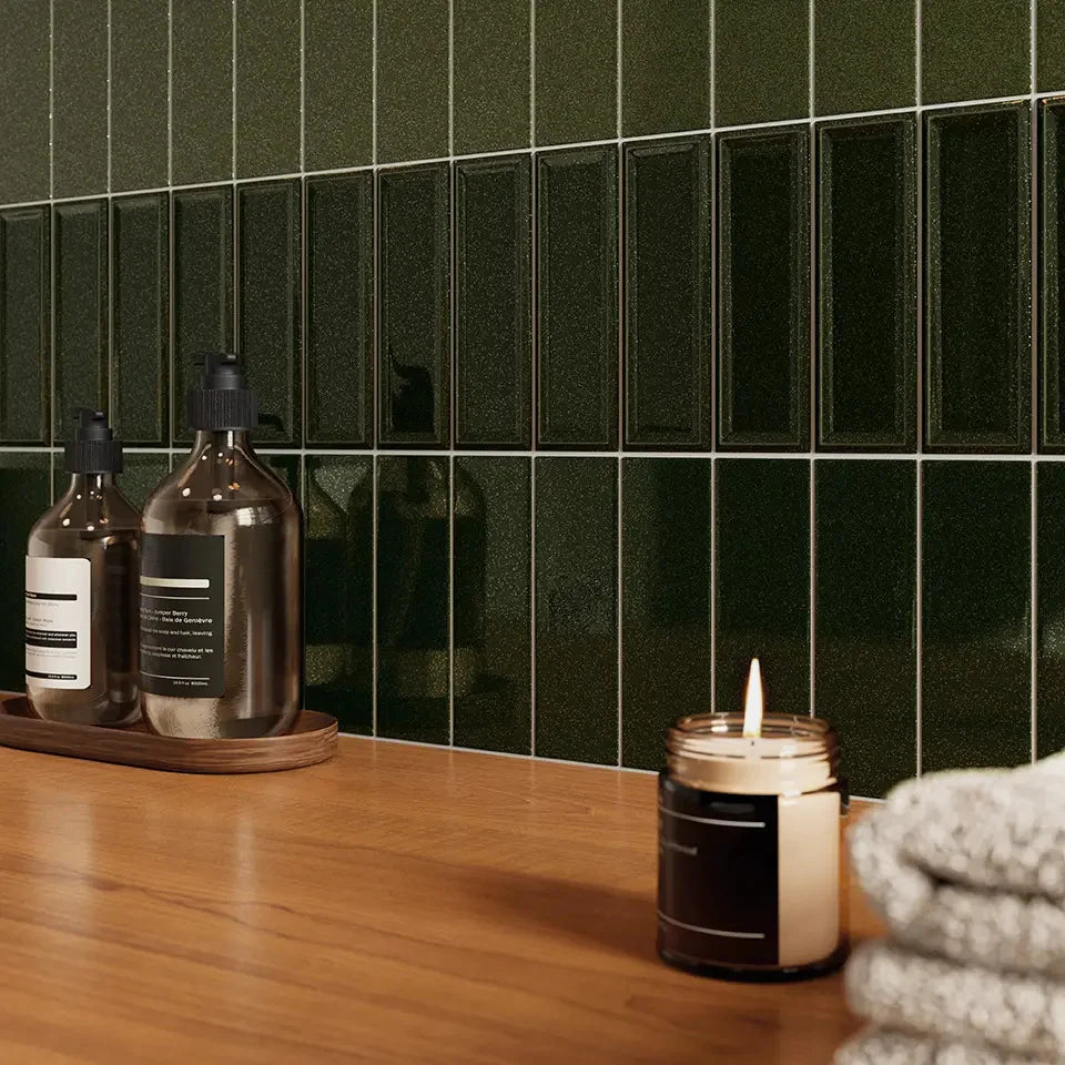Micare Rim Evergreen Dark Gloss 50x150mm tiles installed as a dark green gloss feature wall behind a timber vanity with soap dispensers and a lit candle.