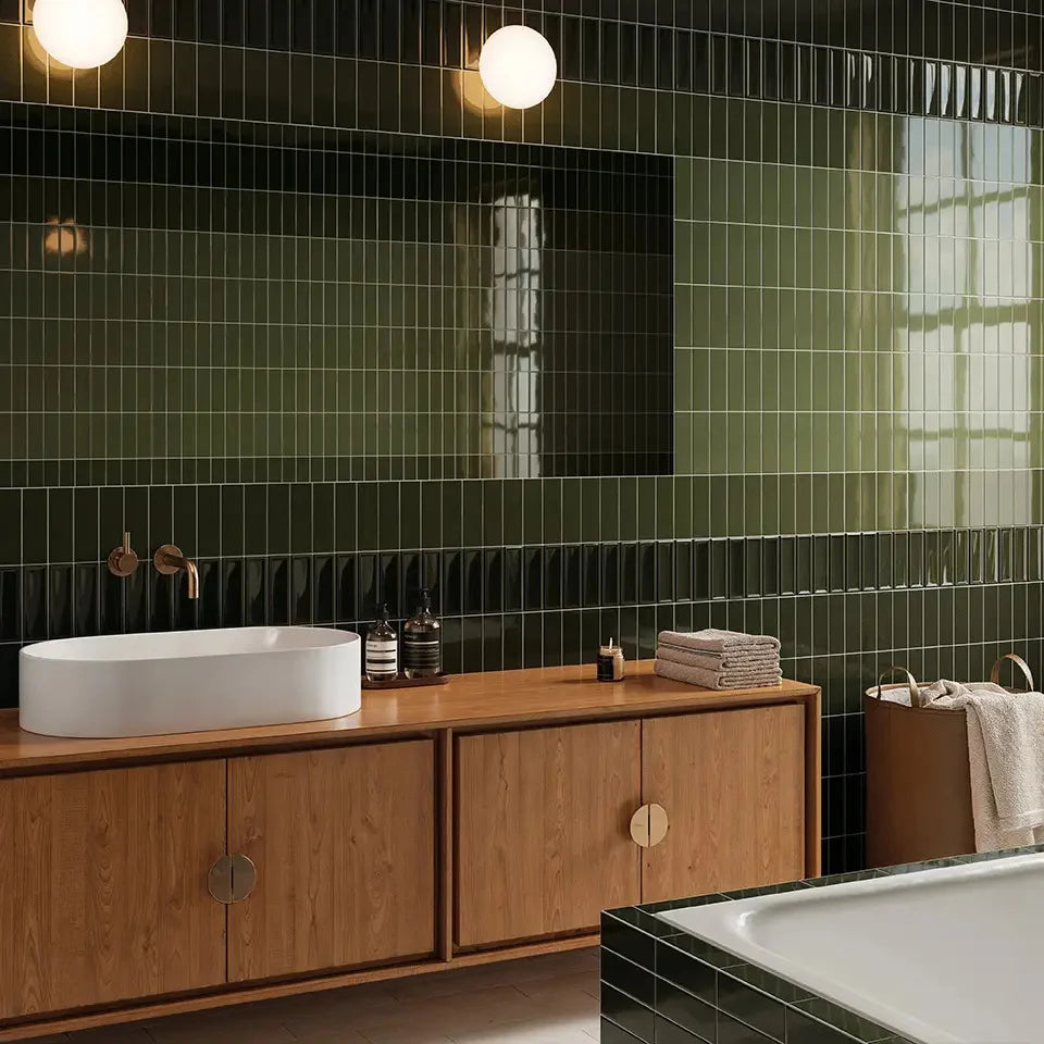 Micare Rim Evergreen Dark Gloss 50x150mm tiles covering a full bathroom wall behind a timber vanity with white vessel sink and globe pendant lights.