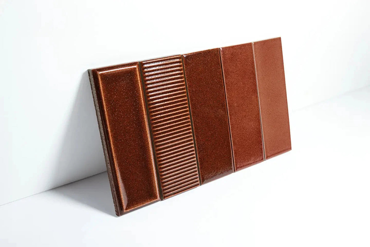 Micare Rim Saffron Dark Gloss 50x150mm ceramic tiles displayed as a sample board showing three surface textures: bevelled, ribbed, and flat in a rich warm brown gloss finish.