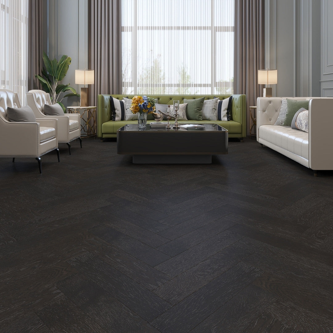 Midnight Grey iDesign Herringbone Flooring 15/3mm installed in a luxury living room with green velvet sofa, cream armchairs, and floor-length curtains.