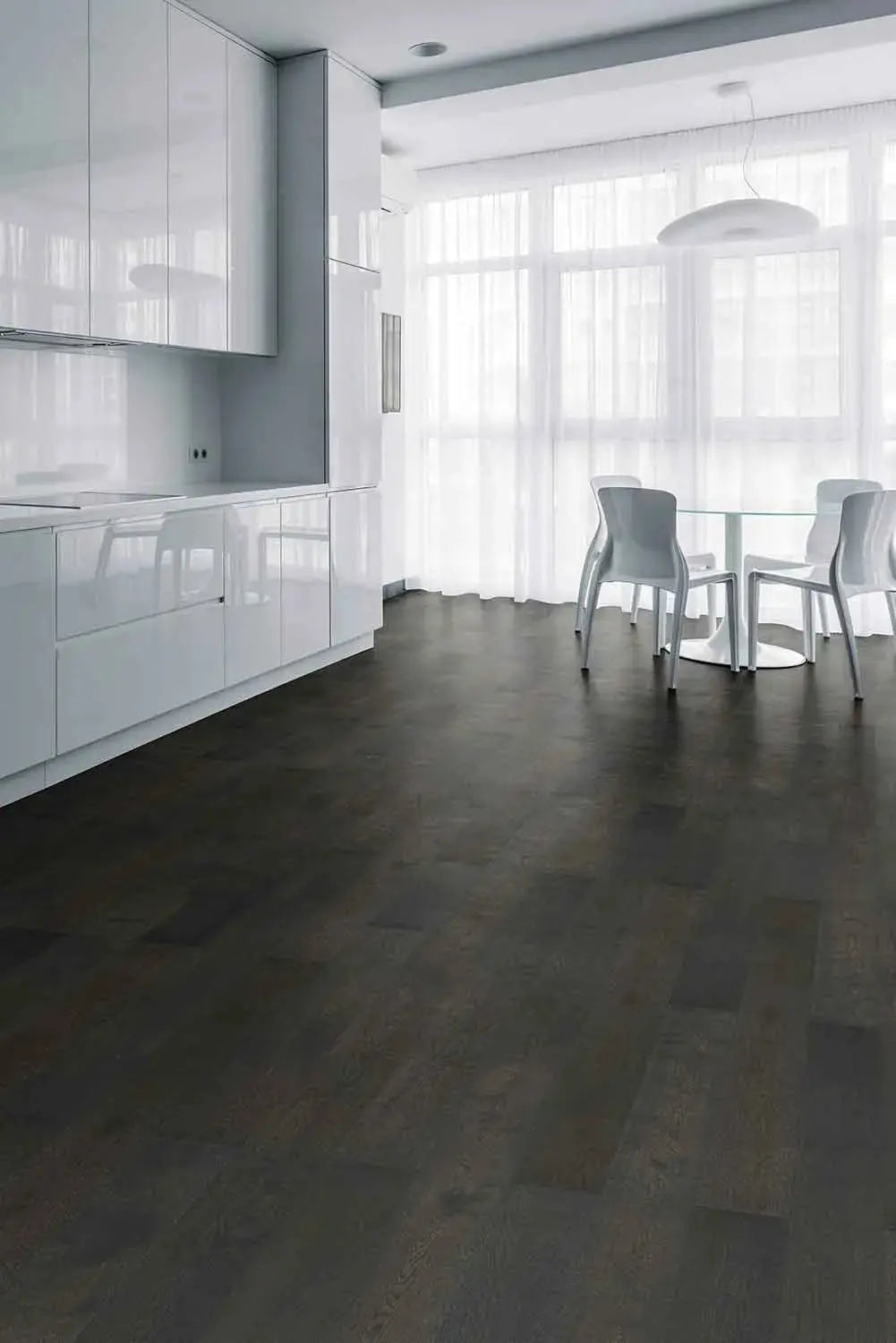 Midnight Grey iDesign15 Oak Flooring 15/3mm installed in a modern open-plan kitchen and dining area with white gloss cabinets, glass dining table, and sheer curtains.