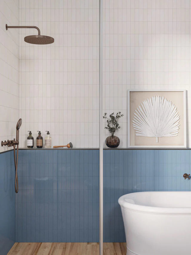 Mini Pure White Glossy 50x150mm tiles covering the upper shower walls above blue ribbed wainscoting, paired with a rainfall showerhead and freestanding bathtub.