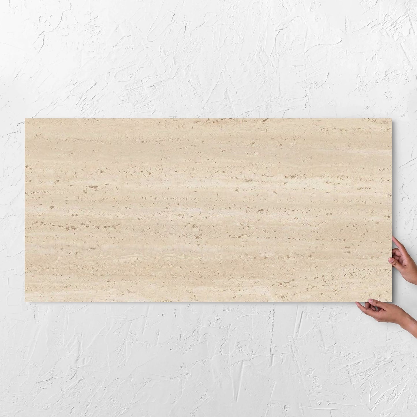 Hands holding a Tallow Vein Cut Travertine Look Beige 600x1200mm tile against a white rendered wall, showing the tile surface