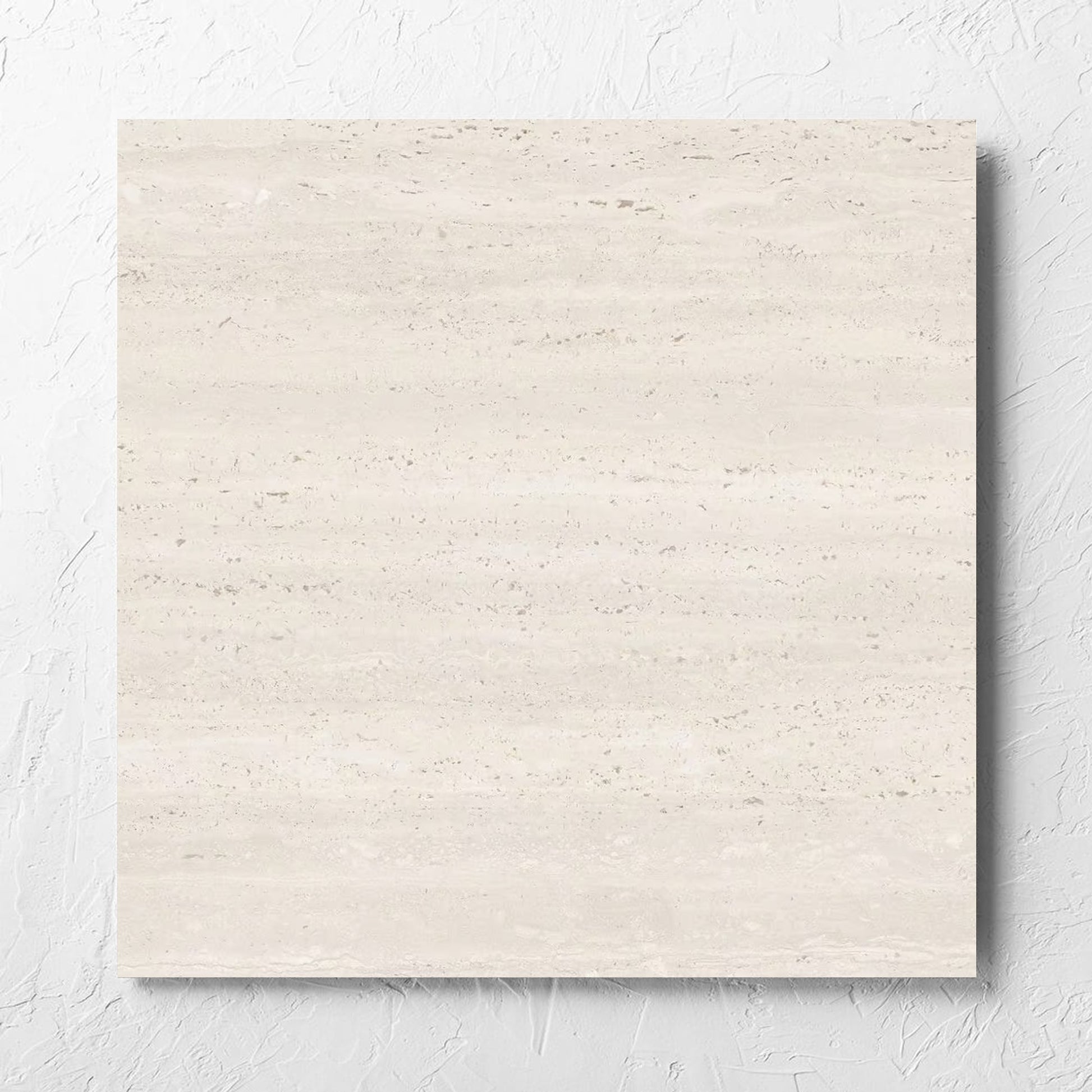 Tallow Vein Cut Travertine Look Ivory 600x600mm tile laid flat on a white rendered wall, showing the beige matt surface