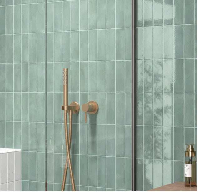 Miyako Oil Blue Gloss 50x150mm tiles covering a walk-in shower wall, paired with brushed brass fixtures and a frameless glass screen.