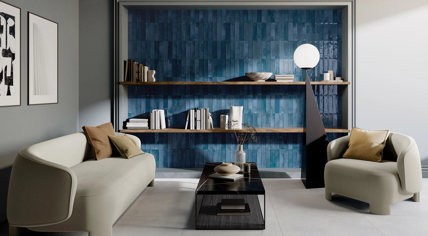 Mojave Blue Brick 60x250mm glossy teal tiles covering a recessed living room feature wall behind open timber shelving, cream sofas, and a globe floor lamp.