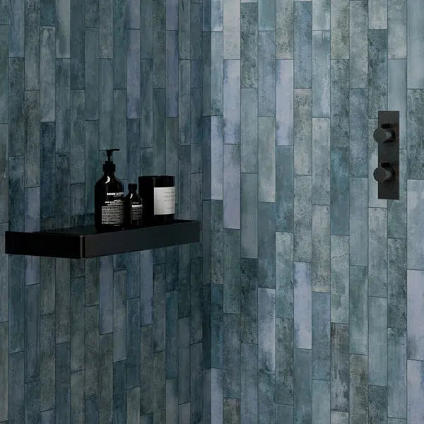 Mojave Denim Brick 60x250mm tiles installed in a modern shower enclosure with matte black thermostatic valve and floating shelf holding toiletries.