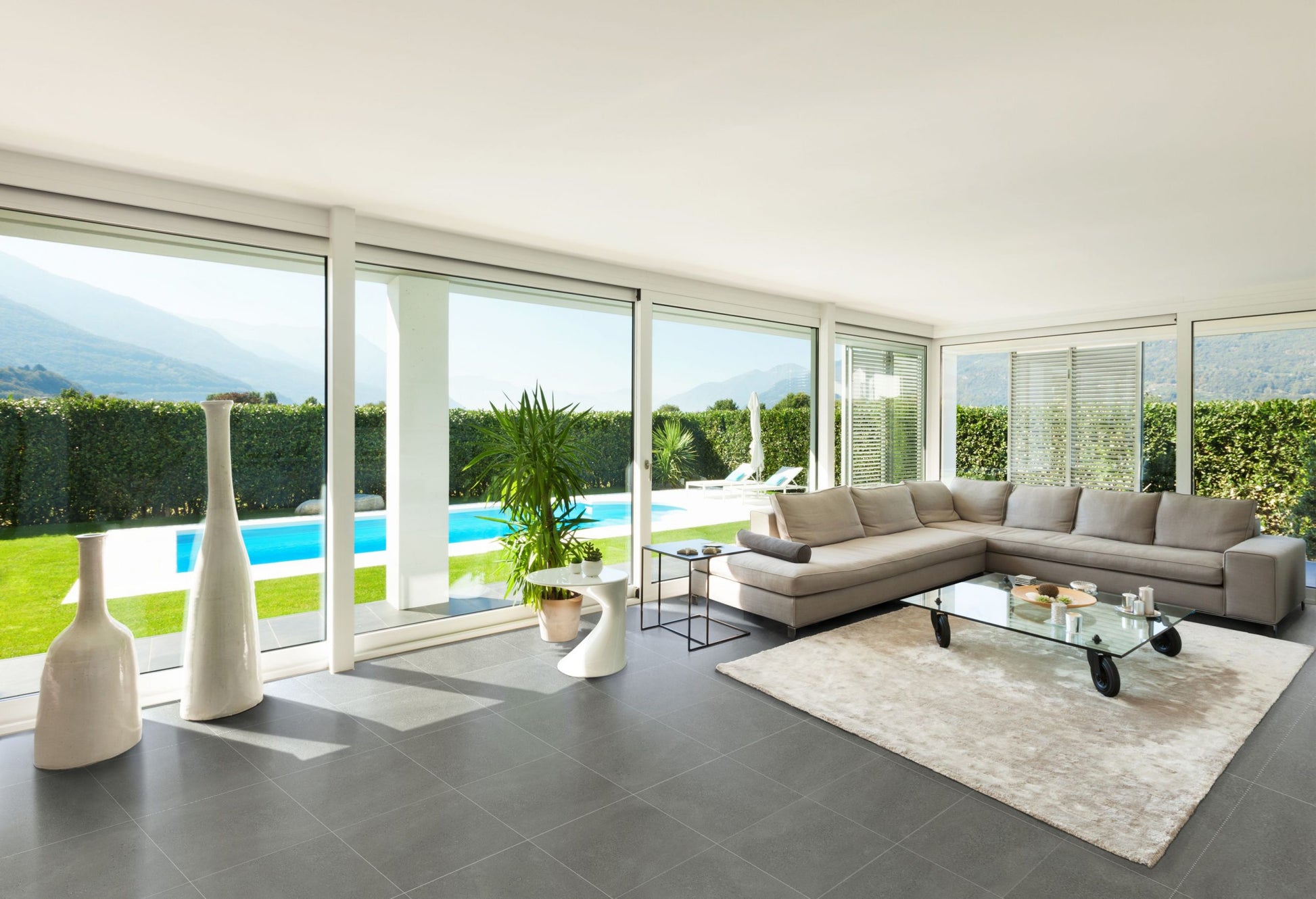 Moonstone Oyster Matte 300x600mm large-format grey tiles laid on a modern living room floor with floor-to-ceiling windows overlooking a pool.