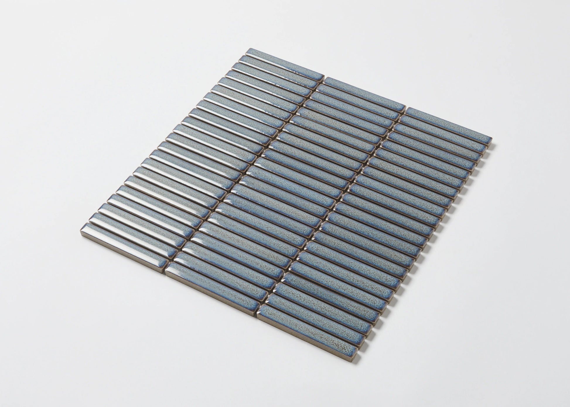 Pack shot of Mottled Grey Gloss Porcelain Glazed KitKat 12x92mm mosaic tile sheet showing slim blue-grey finger tiles with a speckled glaze finish arranged in parallel rows.