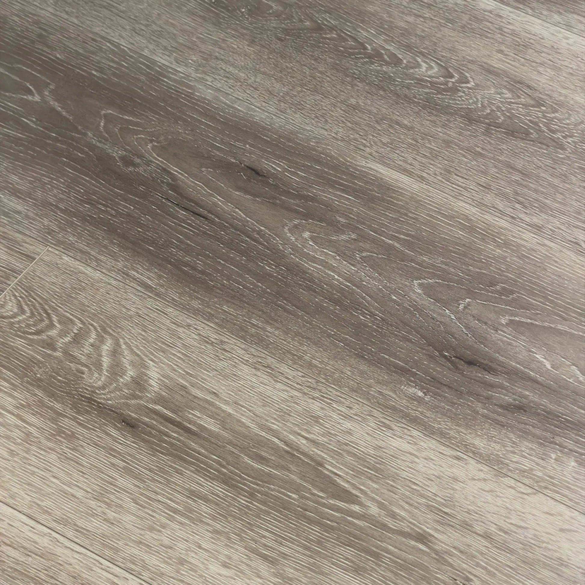 Close-up texture shot of Mystic Grey Urban Laminate 12mm Flooring 12mm showing detailed grey wood grain pattern with natural knots and subtle white streaking.