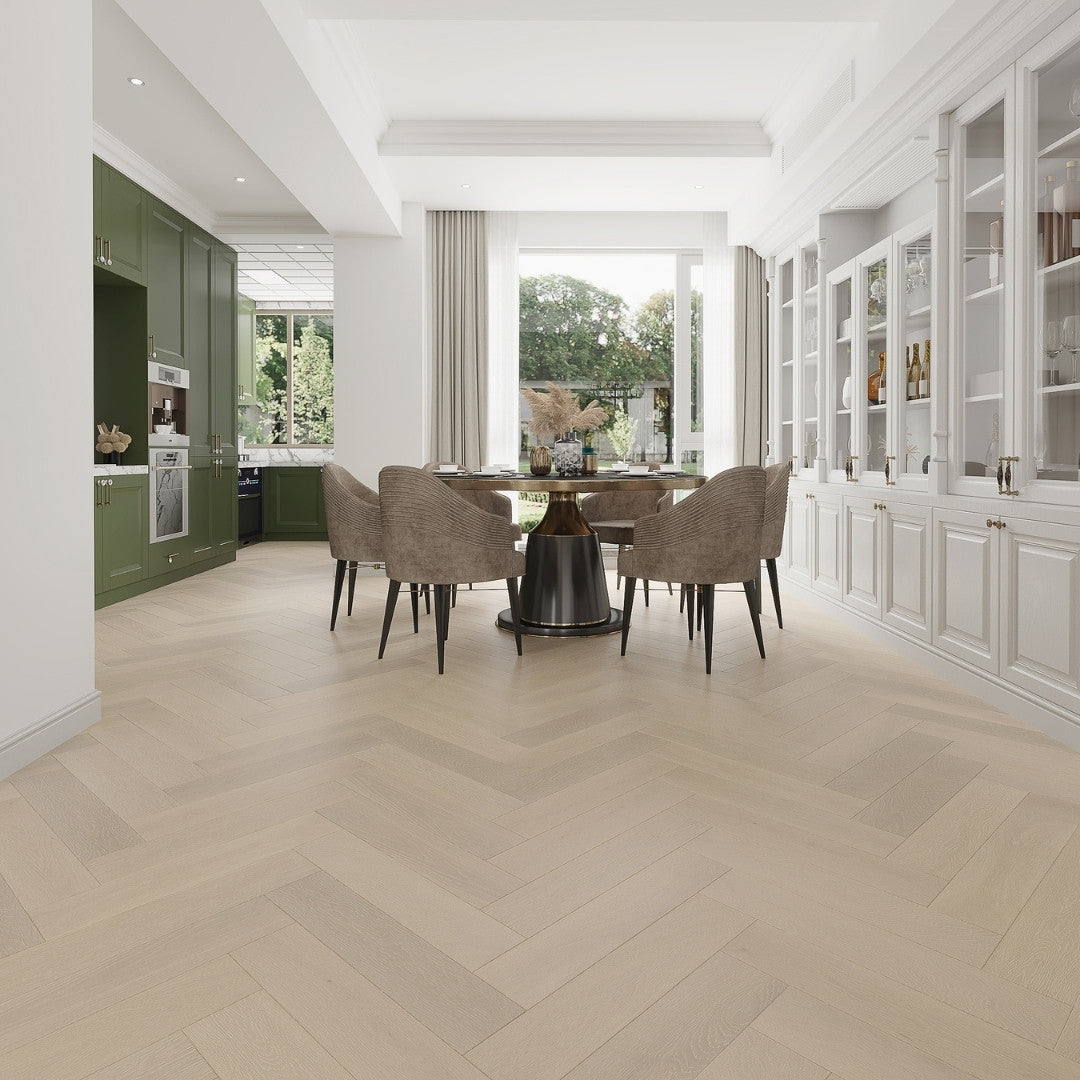 Natural Limed iDesign Herringbone Flooring 15/3mm installed in an open-plan dining room with green kitchen cabinetry, a round dark dining table, and large garden-facing windows.