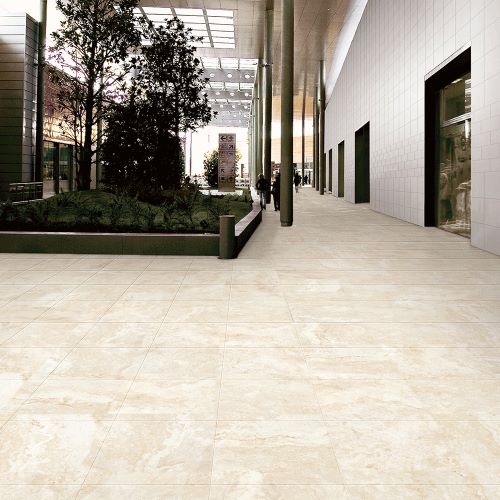 New Travertino Ivory Matt Rect 600x600mm tiles installed across a spacious modern commercial lobby floor with indoor landscaping and glass canopy.