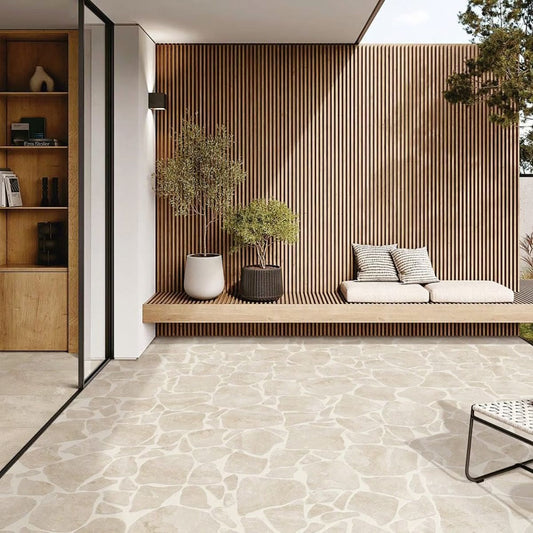 Norcia Beige Crazy Pave 10Mm 600x600mm tiles covering a modern outdoor patio floor beside a timber slat wall with built-in bench seating and potted olive trees.