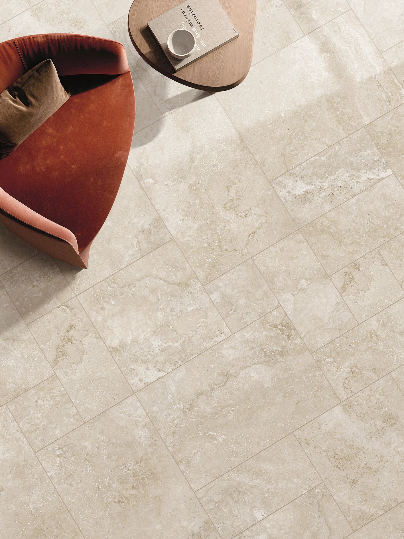 Norcia Beige French Pattern 400x600mm porcelain floor tiles installed in a living room styled with a rust-red armchair and round timber coffee table.