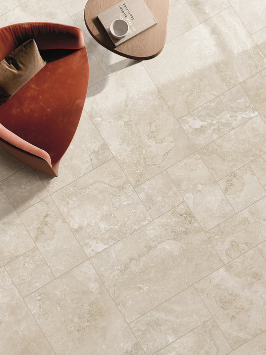 Norcia Beige French Pattern 400x600mm porcelain floor tiles installed in a living room styled with a rust-red armchair and round timber coffee table.