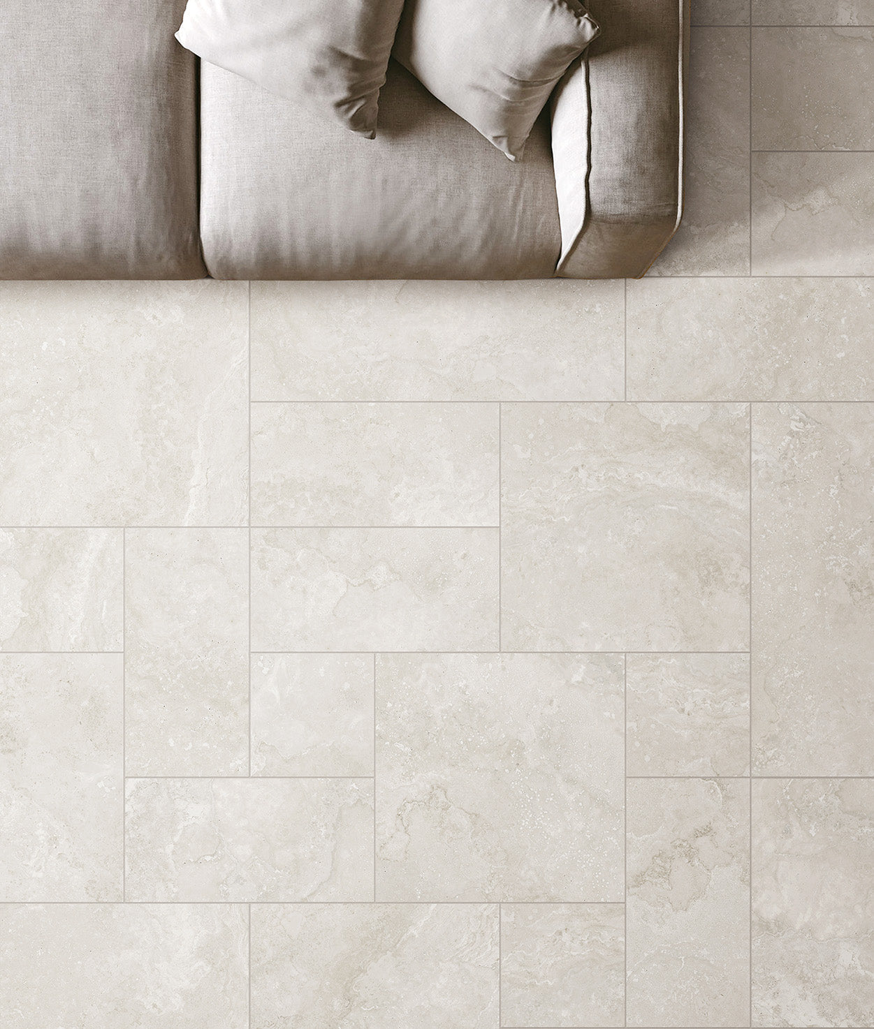 Norcia Light French Pattern 400x600mm cream stone-look porcelain tiles installed on a living room floor beneath a neutral linen sofa with cushions.
