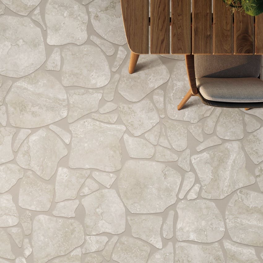 Norcia Silver Crazy Pave 600x600mm porcelain tiles installed on an outdoor patio floor in a light beige irregular stone pattern beside a timber slatted chair.