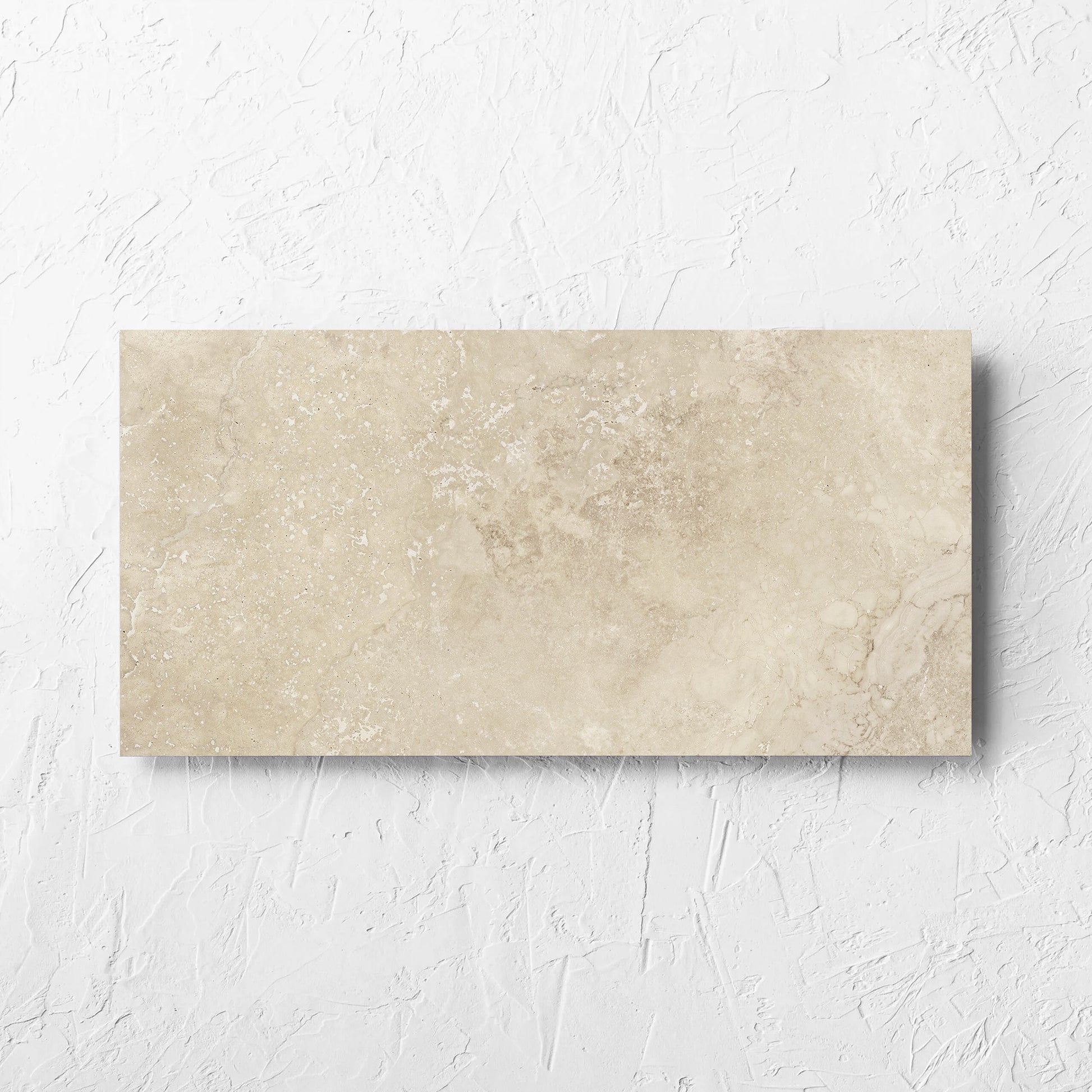 Norcia Travertine Beige 300x600mm tile laid flat on a white rendered wall, showing the beige matt surface