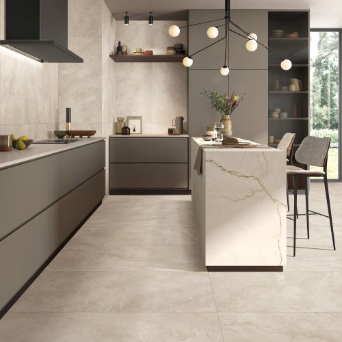 Norcia Travertine Beige Honed 600x600mm tiles installed on a modern open-plan kitchen floor with handleless grey cabinetry, marble island, and pendant lighting.