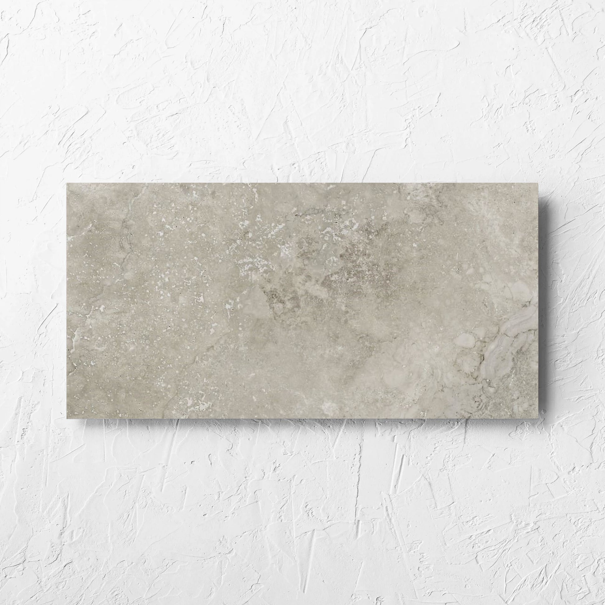 Norcia Travertine Grey 300x600mm tile laid flat on a white rendered wall, showing the tile surface