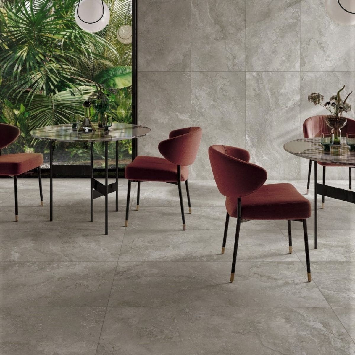 Norcia Travertine Grey 600x1200mm large-format tiles covering the floor and wall of a sophisticated dining space with burgundy velvet chairs and marble-top tables.