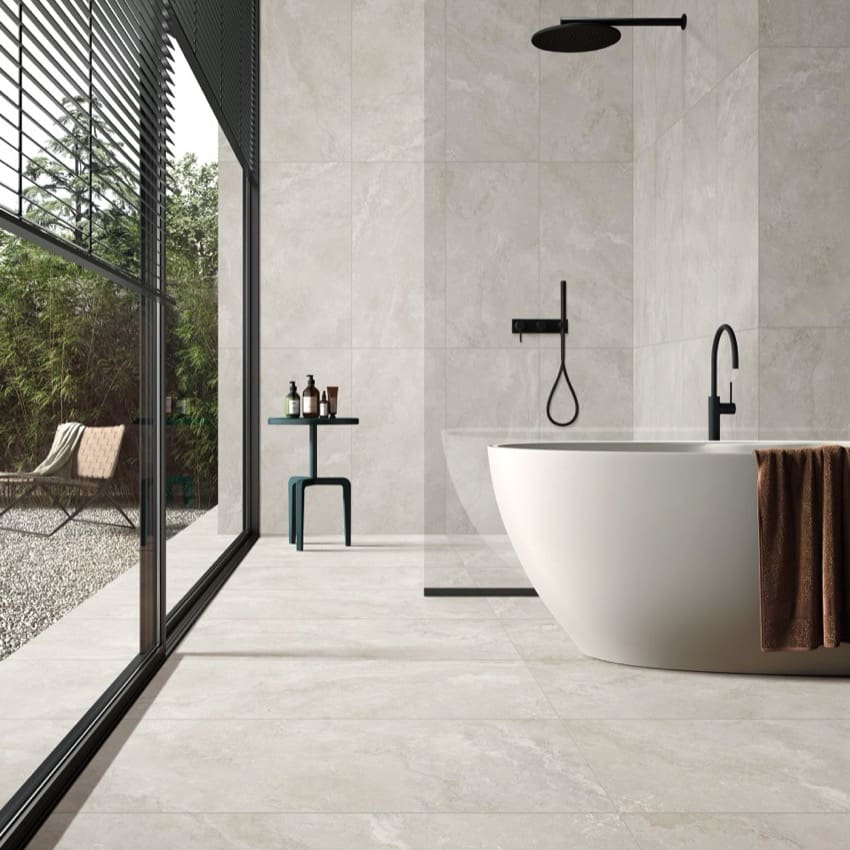 Norcia Travertine Light Bamboo Feature 600x1200mm tiles covering the floor and walls of a contemporary bathroom featuring a freestanding white bath and matte black fixtures.