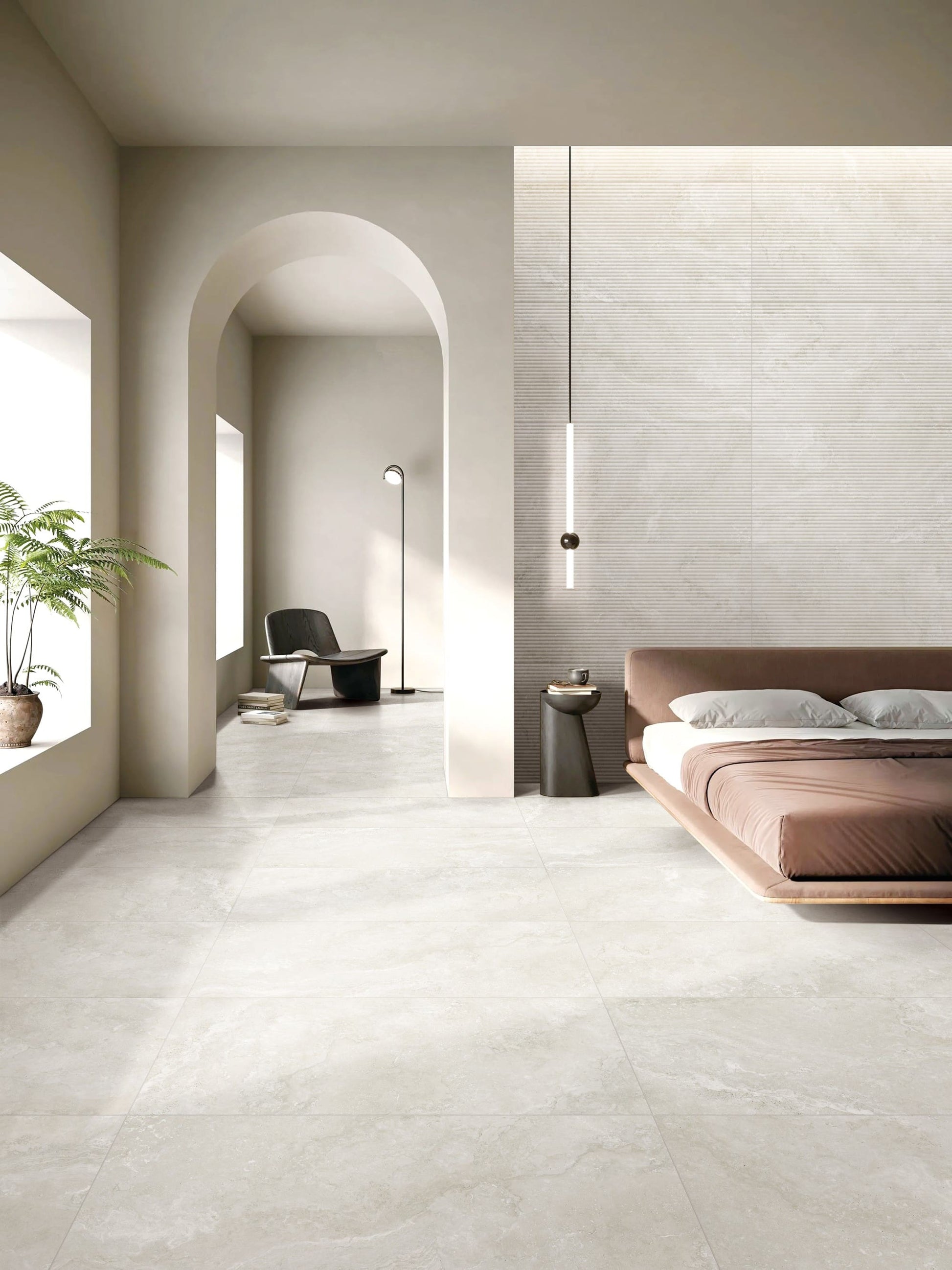 Norcia Travertine Light Bamboo Feature 600x1200mm tile installed as a textured bedroom feature wall behind a low-profile bed with a pendant light and arched hallway.