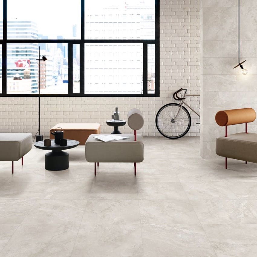 Norcia Travertine Light Bamboo Feature 600x1200mm tiles installed on a spacious modern lounge floor, styled with contemporary ottomans, pendant lighting, and white brick feature walls.