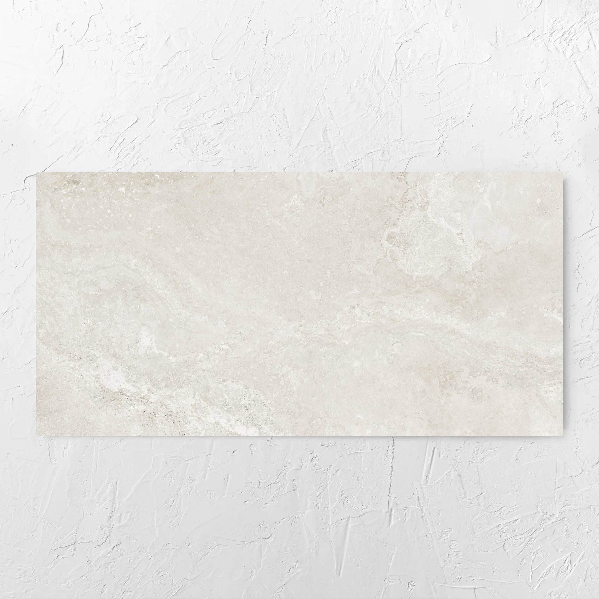 Norcia Travertine Light Honed 600x1200mm tile laid flat on a white rendered wall, showing the light grey honed surface