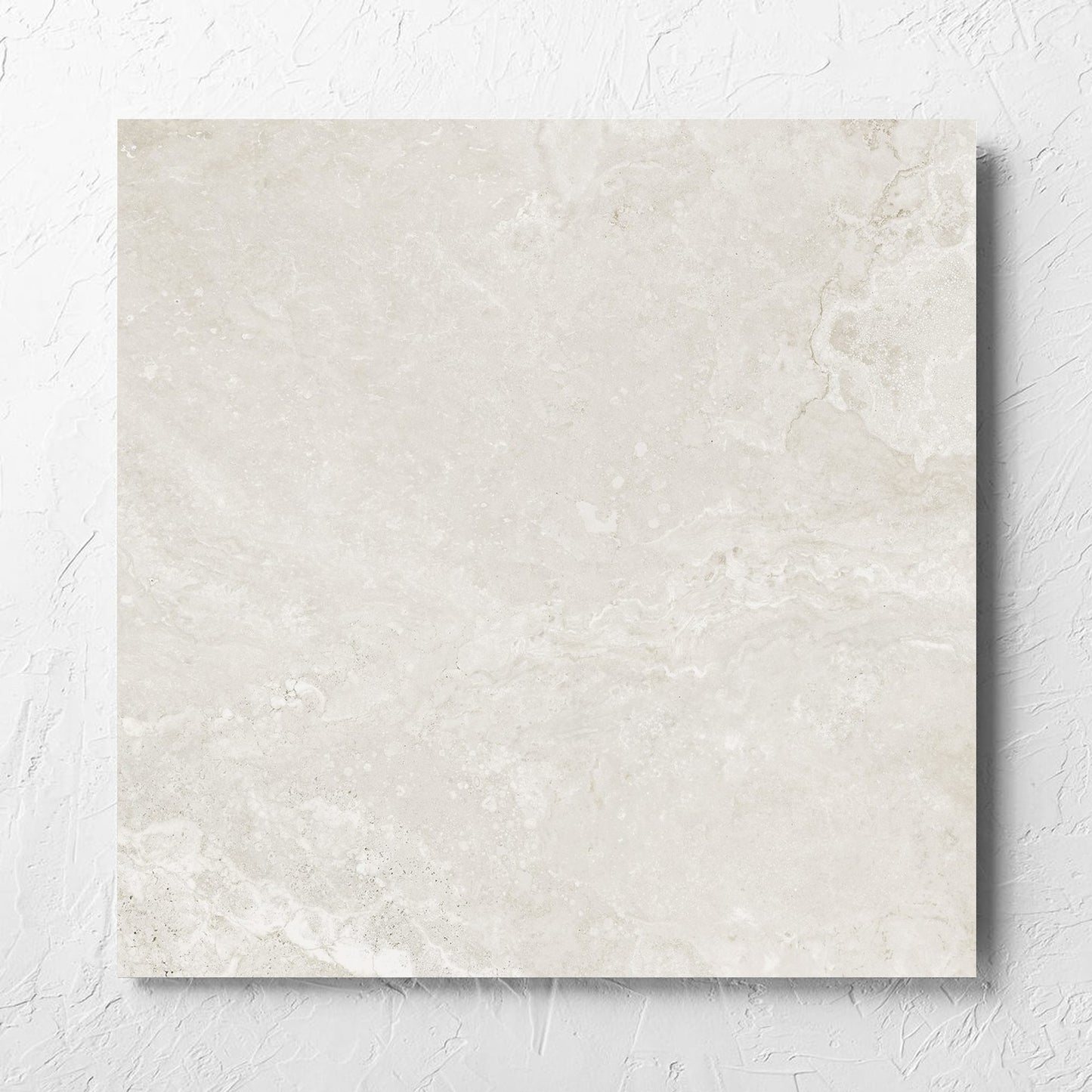 Norcia Travertine Light Honed 600x600mm tile laid flat on a white rendered wall, showing the tile surface