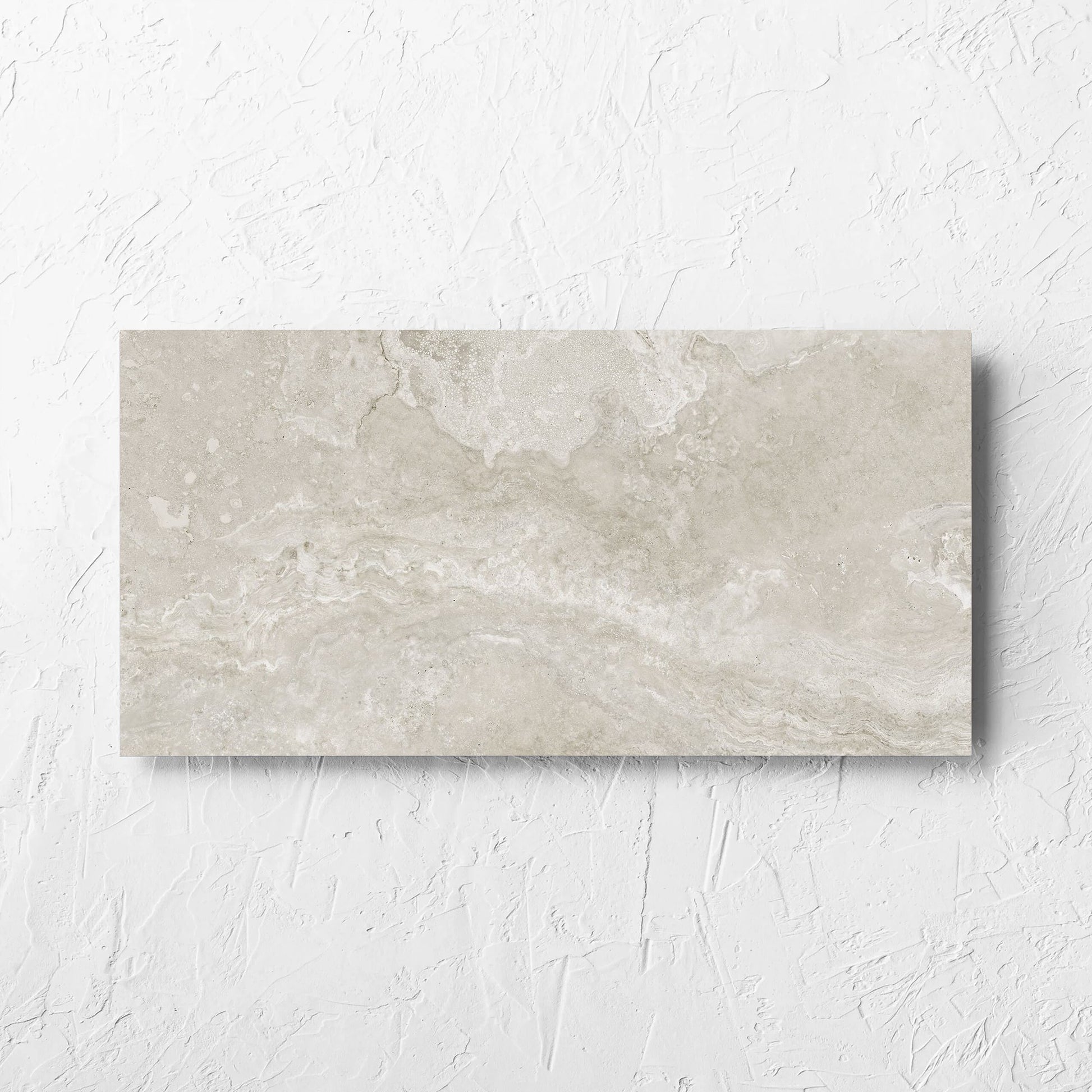 Norcia Travertine Silver 300x600mm tile laid flat on a white rendered wall, showing the tile surface