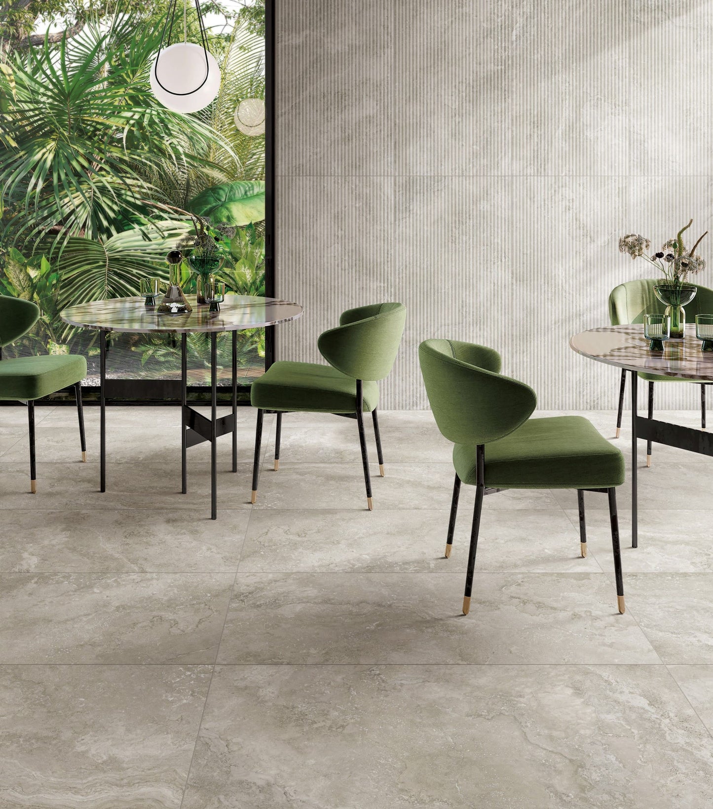 Norcia Travertine Silver 75x300mm large-format grey floor tiles in a modern cafe dining space with green velvet chairs and marble-top tables.