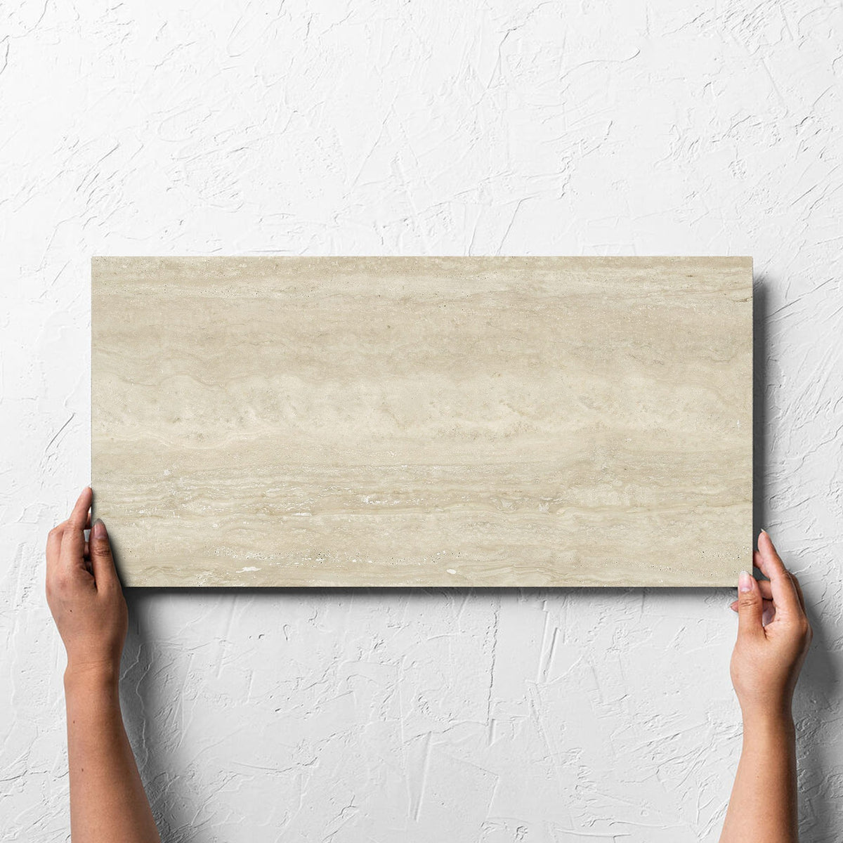 Hand holding a single Norcia Vein Cut Beige 300x600mm tile against a white rendered wall, showing the beige matt surface