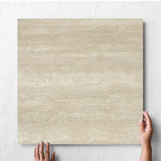 Hand holding a single Norcia Vein Cut Beige 600x600mm tile against a white rendered wall, showing the beige matt surface