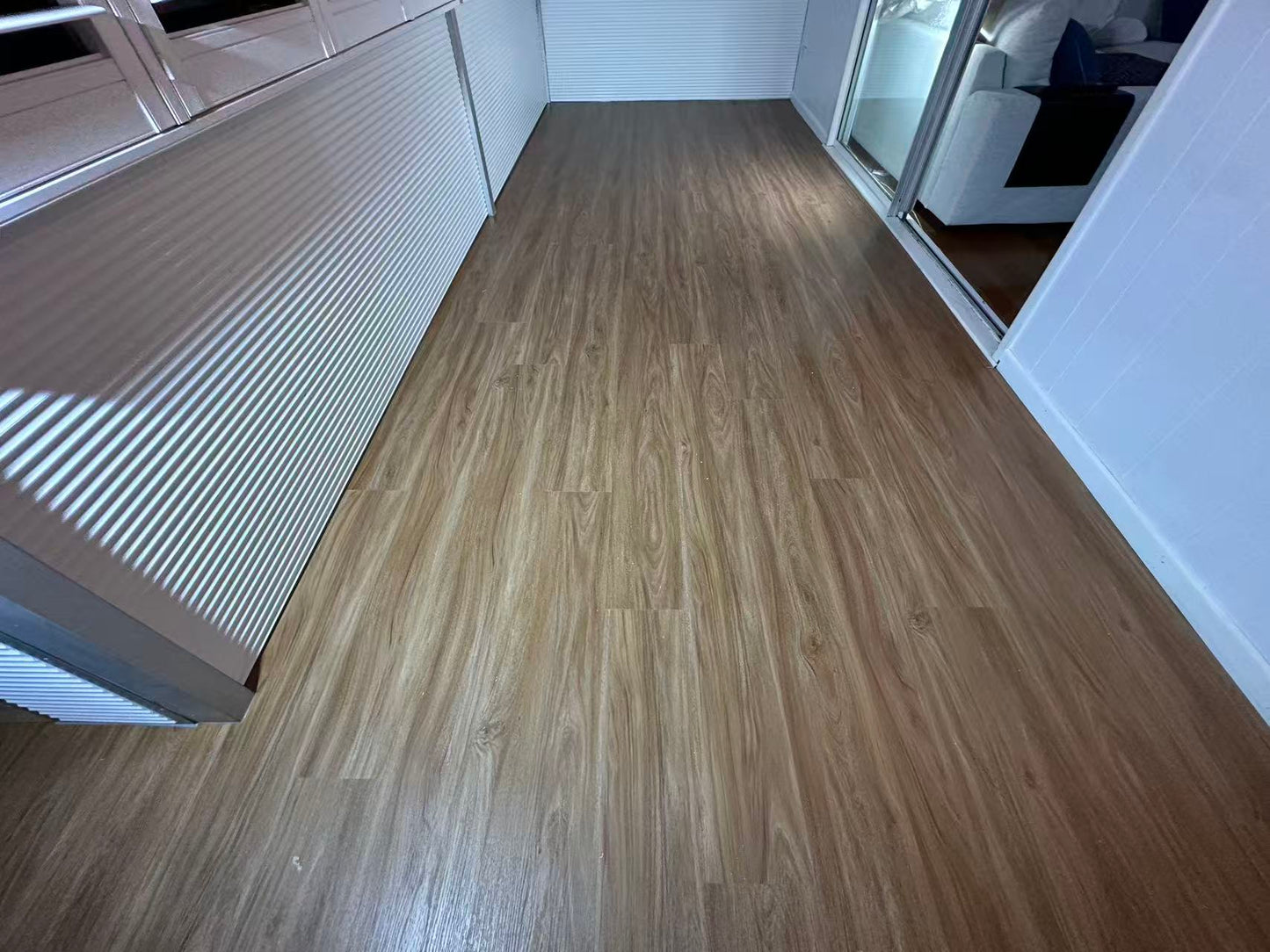 NSW Spotted Gum Elegant SPC Hybrid 6.5mm Flooring 5+1.5mm installed in a narrow balcony hallway with warm brown wood-look planks, white walls, and sliding glass door.