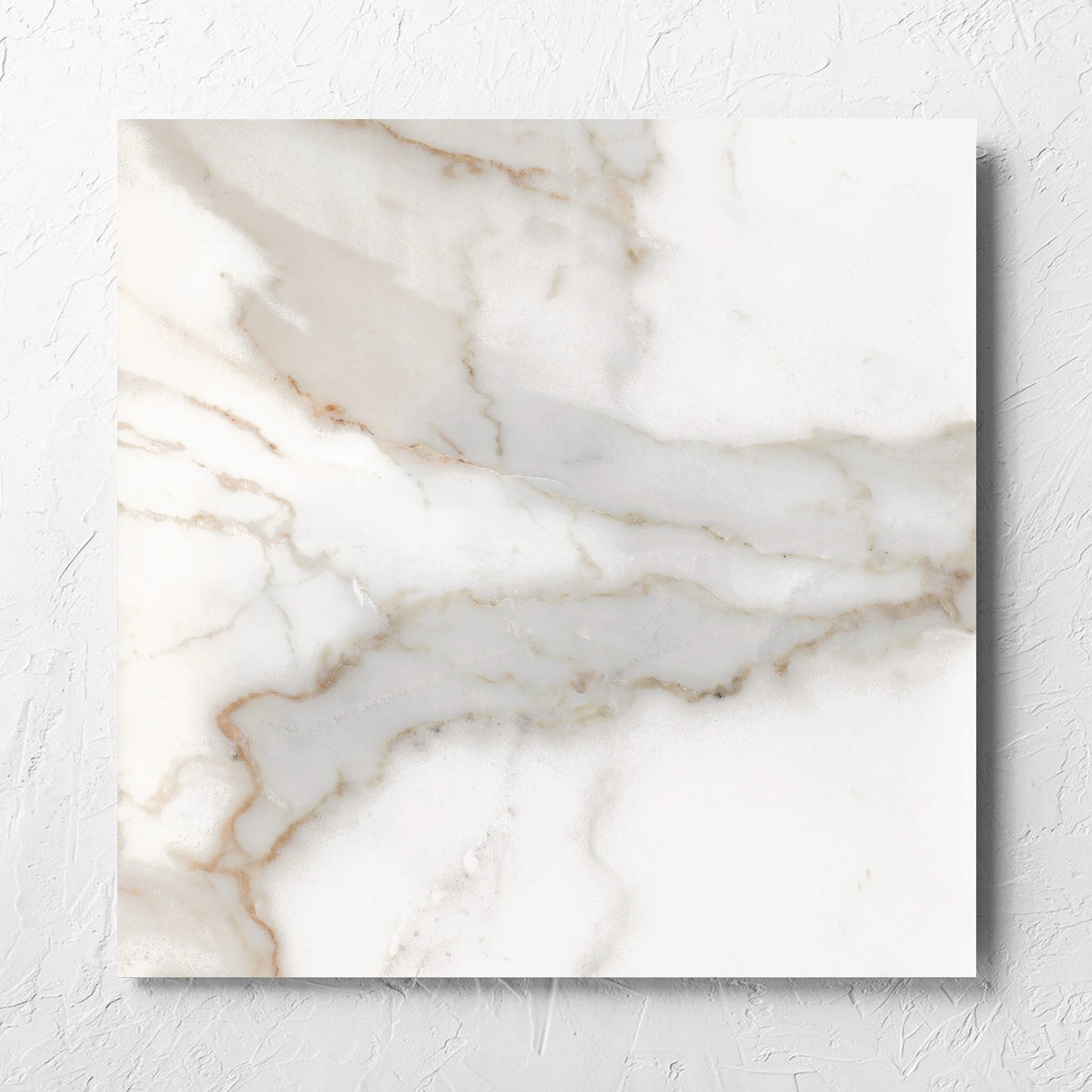 Nuovi Marmi Calacatta Gold Matt 600x600mm tile laid flat on a white rendered wall, showing the matt surface