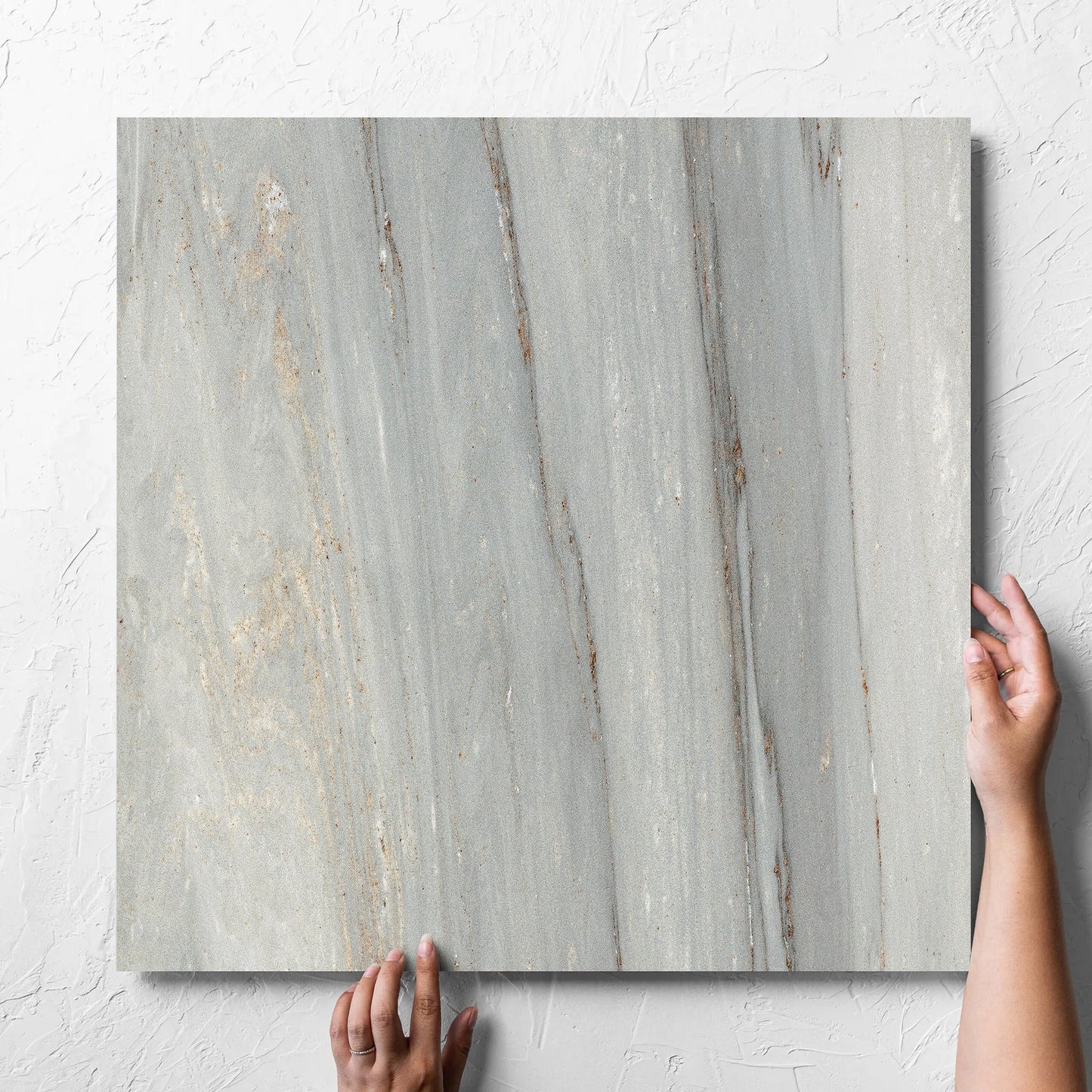 Hand holding a single Nuovi Marmi Palissandro Lappato 600x600mm tile against a white rendered wall, showing the matt surface