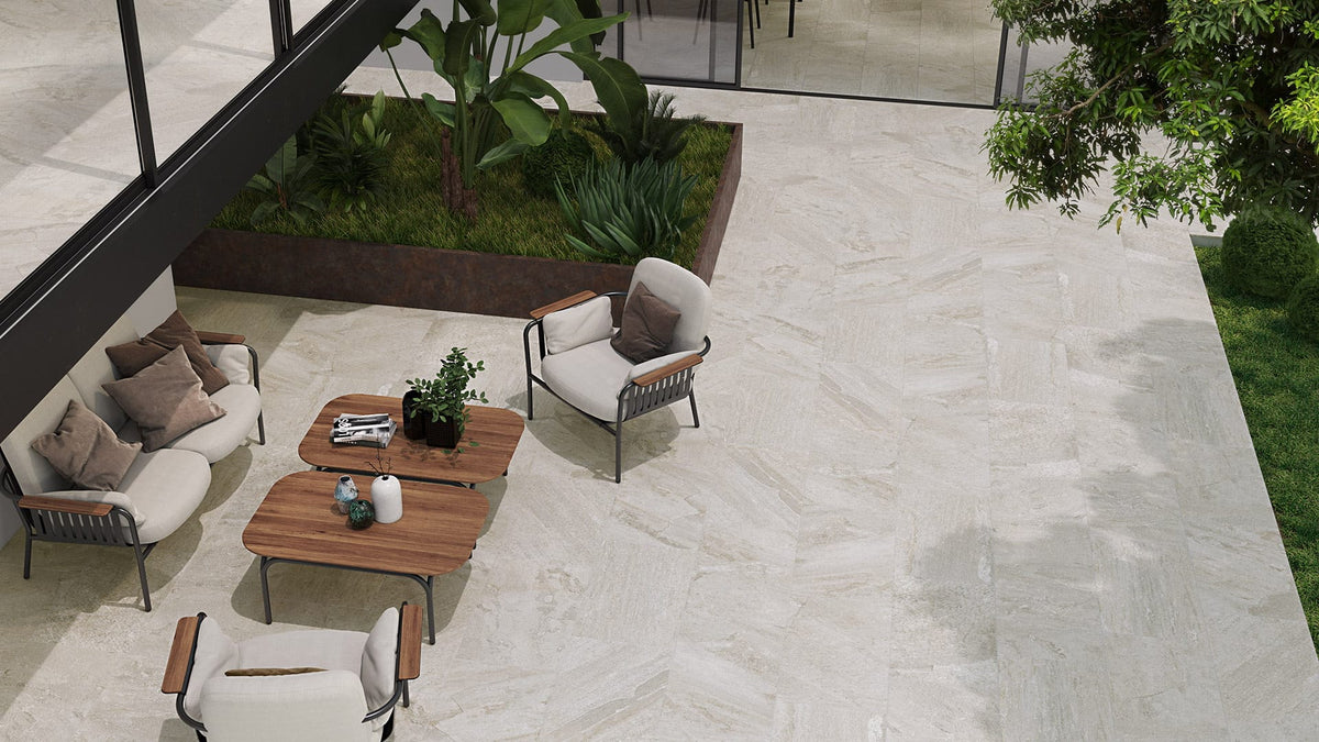 Oberon White Modular French Pattern Structured tiles covering a modern outdoor patio with cream lounge chairs, wooden coffee tables, and tropical garden planter.