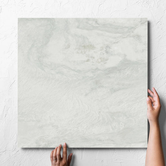 Hand holding a single Onyx White Matt 600x600mm tile against a white rendered wall, showing the matt surface