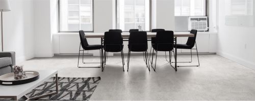 Oslo Bianco Rectified 300x600mm porcelain tile installed as a light grey concrete-look floor in a minimalist open-plan dining and living room with black chairs.
