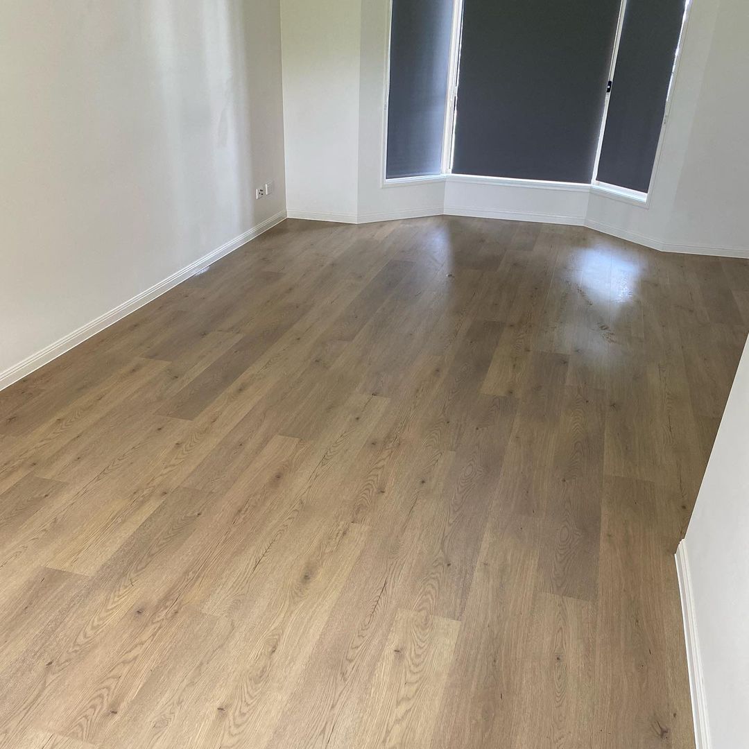 Pale Sand Elegant SPC Hybrid 6.5mm Flooring 5+1.5mm installed in an empty sunlit room with bay windows and white skirting boards.