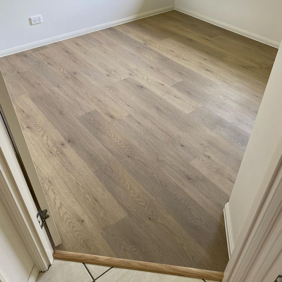 Pale Sand Elegant SPC Hybrid 6.5mm Flooring 5+1.5mm installed in a bright hallway with white skirting boards and a door threshold transition strip.