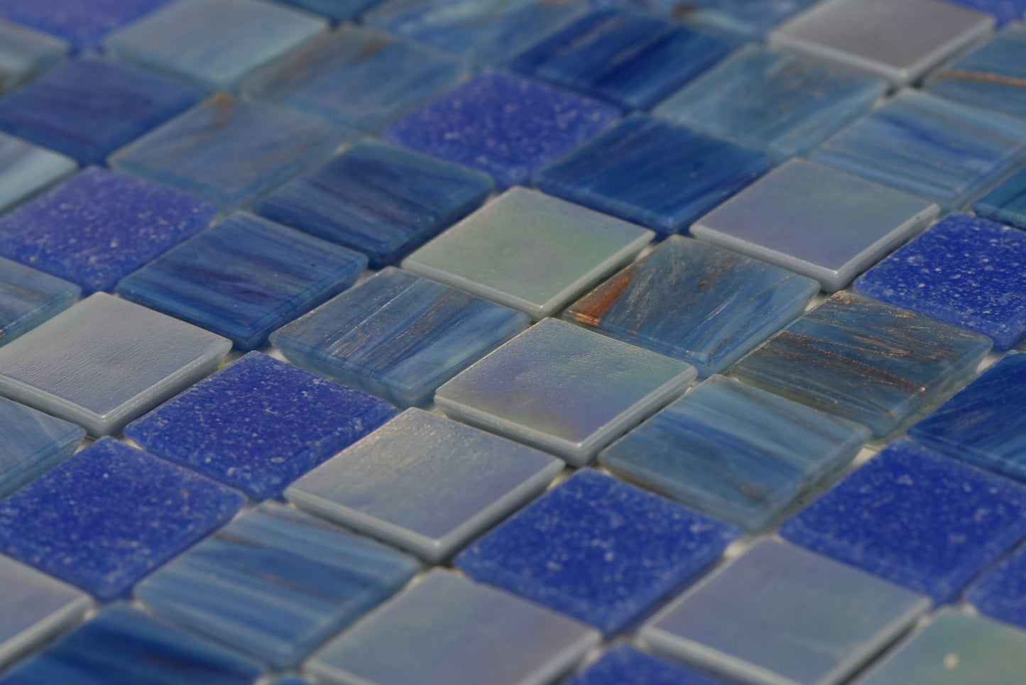 Close-up of Paradise Bali Glass Mosaic Pool Safe 300x300mm tiles showing mixed blue tones with glossy striped and speckled glass finishes.