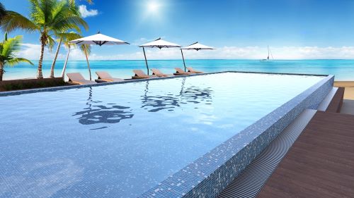 Paradise Madagascar Glass Mosaic Pool Safe 300x300mm tiles lining a luxury infinity pool with ocean views, palm trees, and sun loungers.