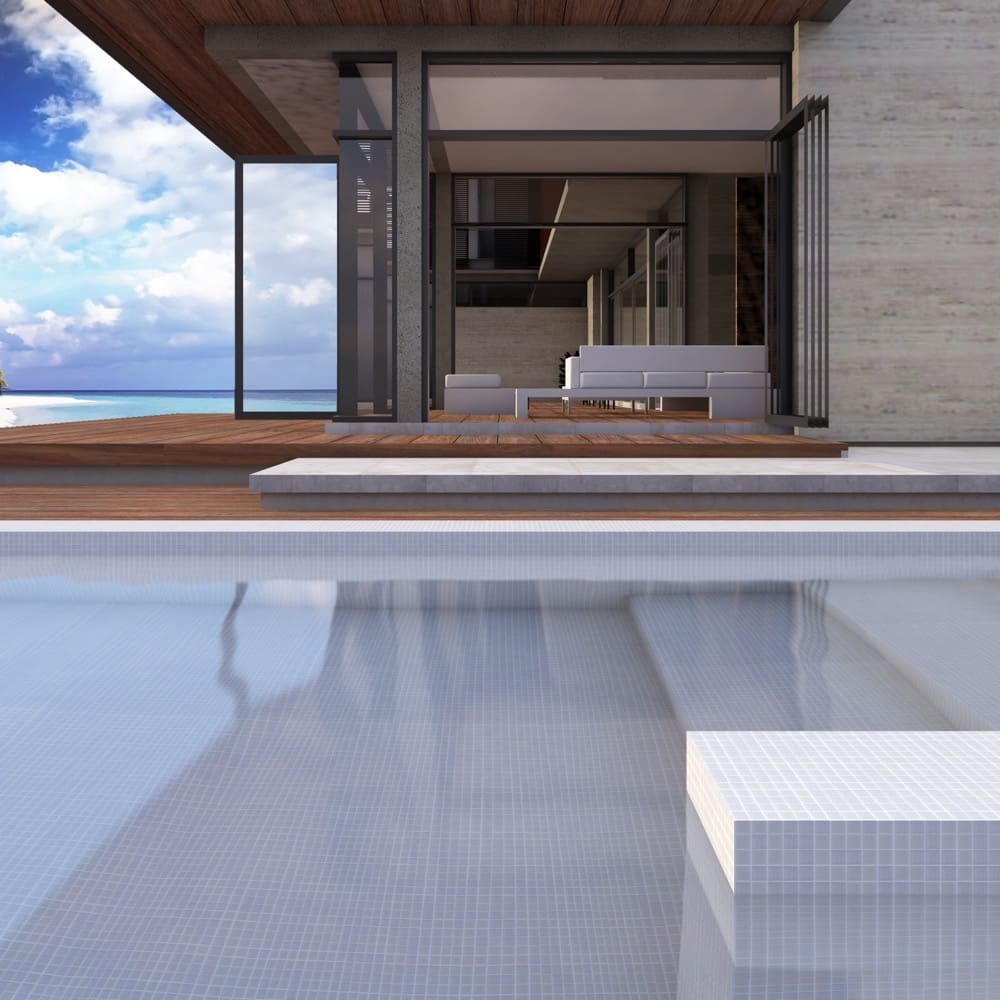 Paradise Noumea Glass Mosaic Pool Safe 300x300mm tiles lining a luxury infinity pool beside a modern beachfront villa with timber decking and ocean views.