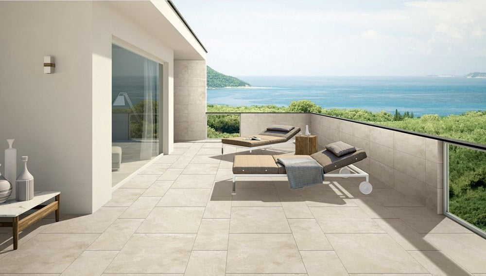 Paradise Stone Ivory External Rectified 600x600mm tiles laid on a spacious modern terrace with sun loungers and panoramic ocean views.