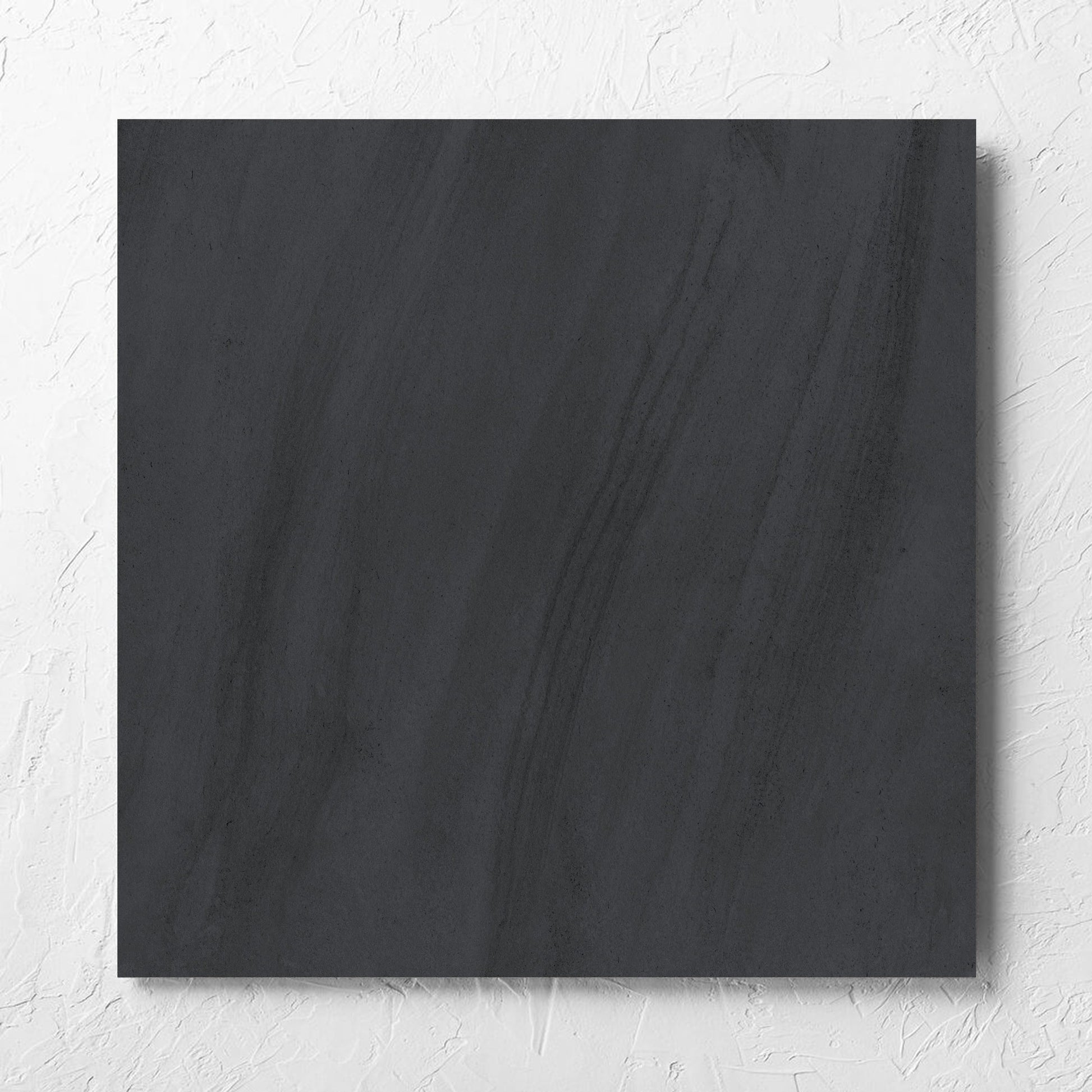 Paris Noir Matt 600x600mm tile laid flat on a white rendered wall, showing the matt surface
