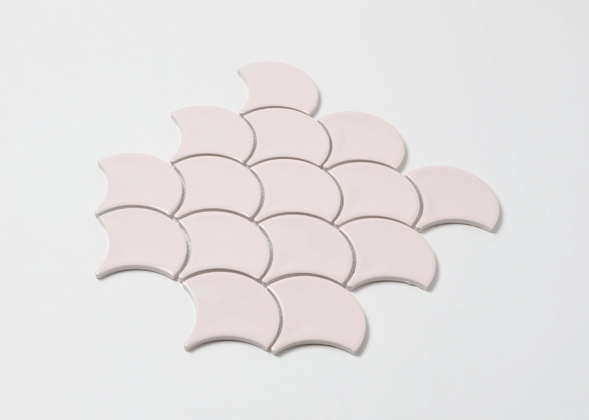 Pack shot of Pastel Pink Gloss Glazed Porcelain Fishscale 95x87mm tiles arranged in an overlapping scallop pattern showing their crescent shape and smooth glossy finish.