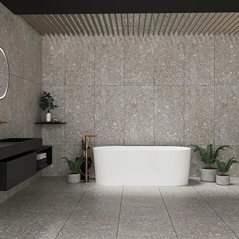 Pedregal Breccia Rectified 300x600mm grey terrazzo-look tiles covering the feature wall and floor of a modern bathroom with a freestanding white bathtub and black floating vanity.