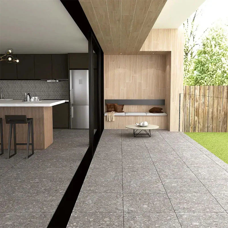 Pedregal Ceppo Rectified 600x1200mm grey stone-look tiles installed across an open-plan outdoor patio and alfresco lounge area with timber cladding and adjacent modern kitchen.